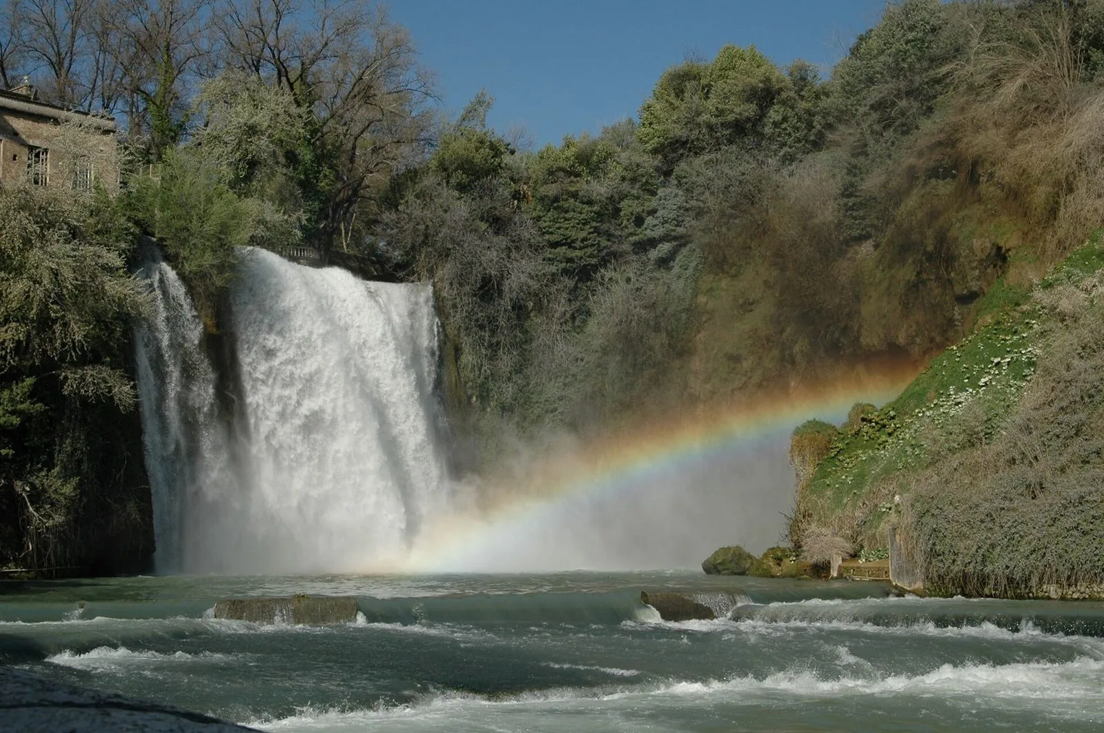 La Cascata Grande di Isola del Liri che precipita tra la vegetazione, con un arcobaleno formato dagli spruzzi sul fiume